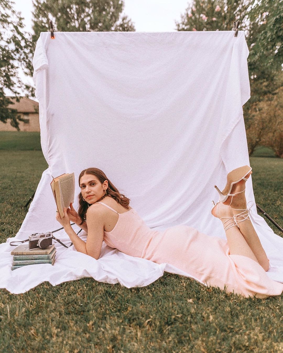 woman in a pink dress reading a book on a photo backdrop