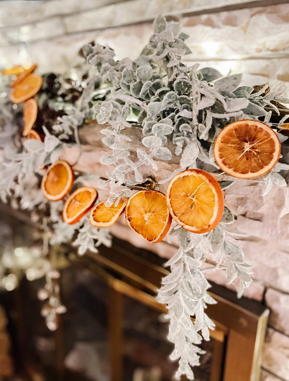 dird orange garland hanging above fireplace with greenery