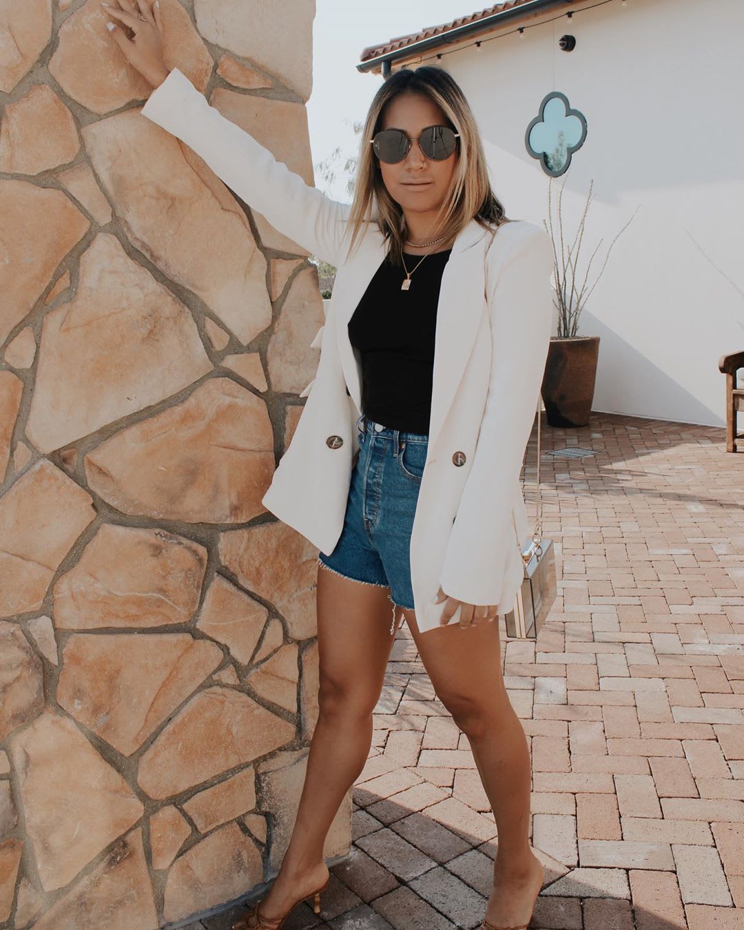 woman wearing a white blazer with black top and cutoffs for early fall outfit