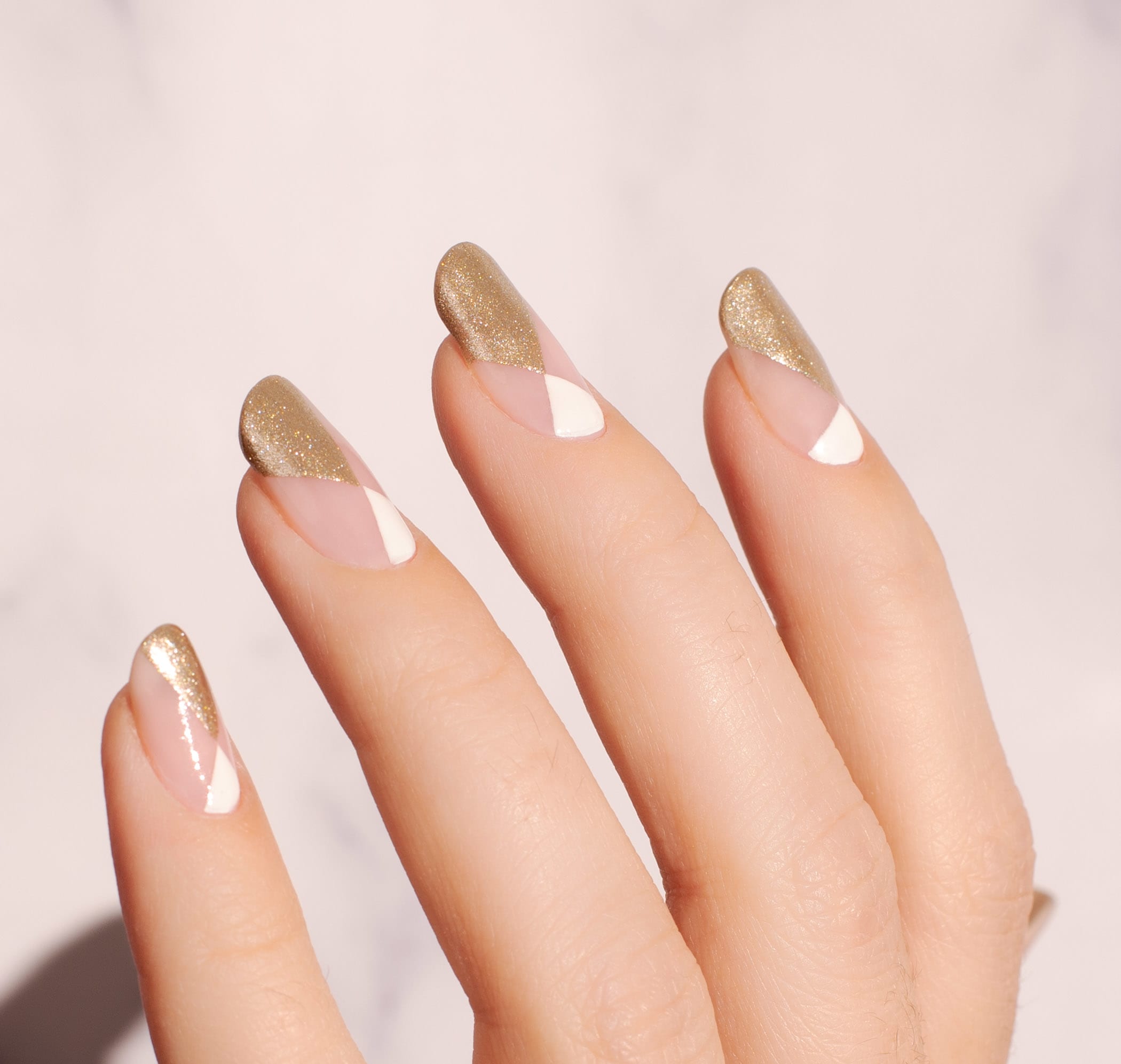 gold and white geometric design on nude nails