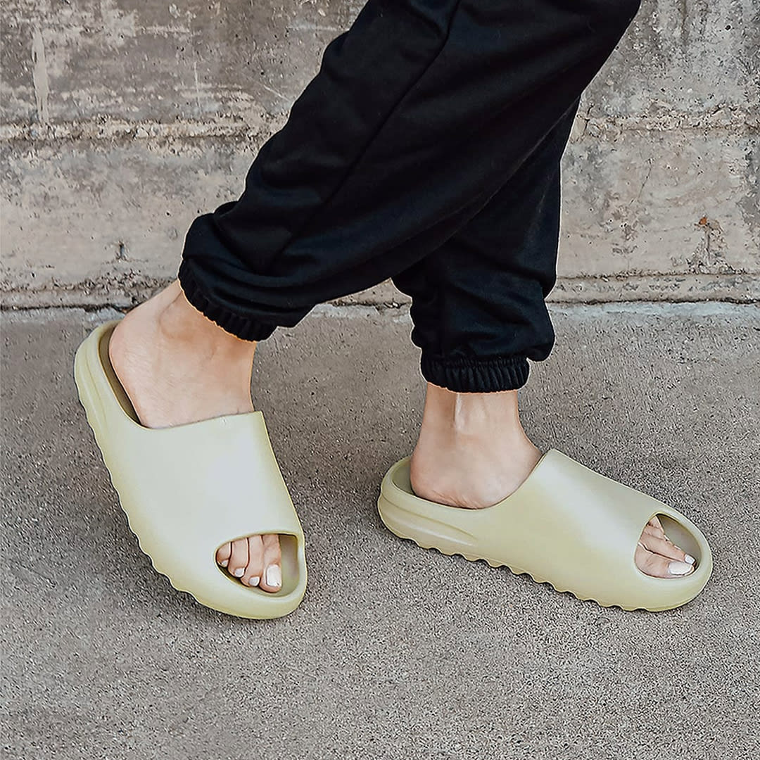 feet in black pants and khaki slide sandals