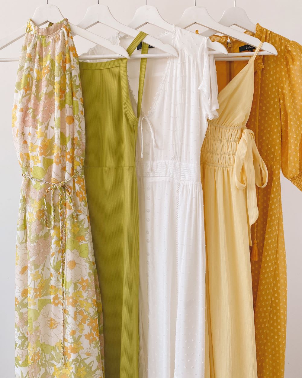 a rack of yellow, green, white, and rust 70s-inspired dresses