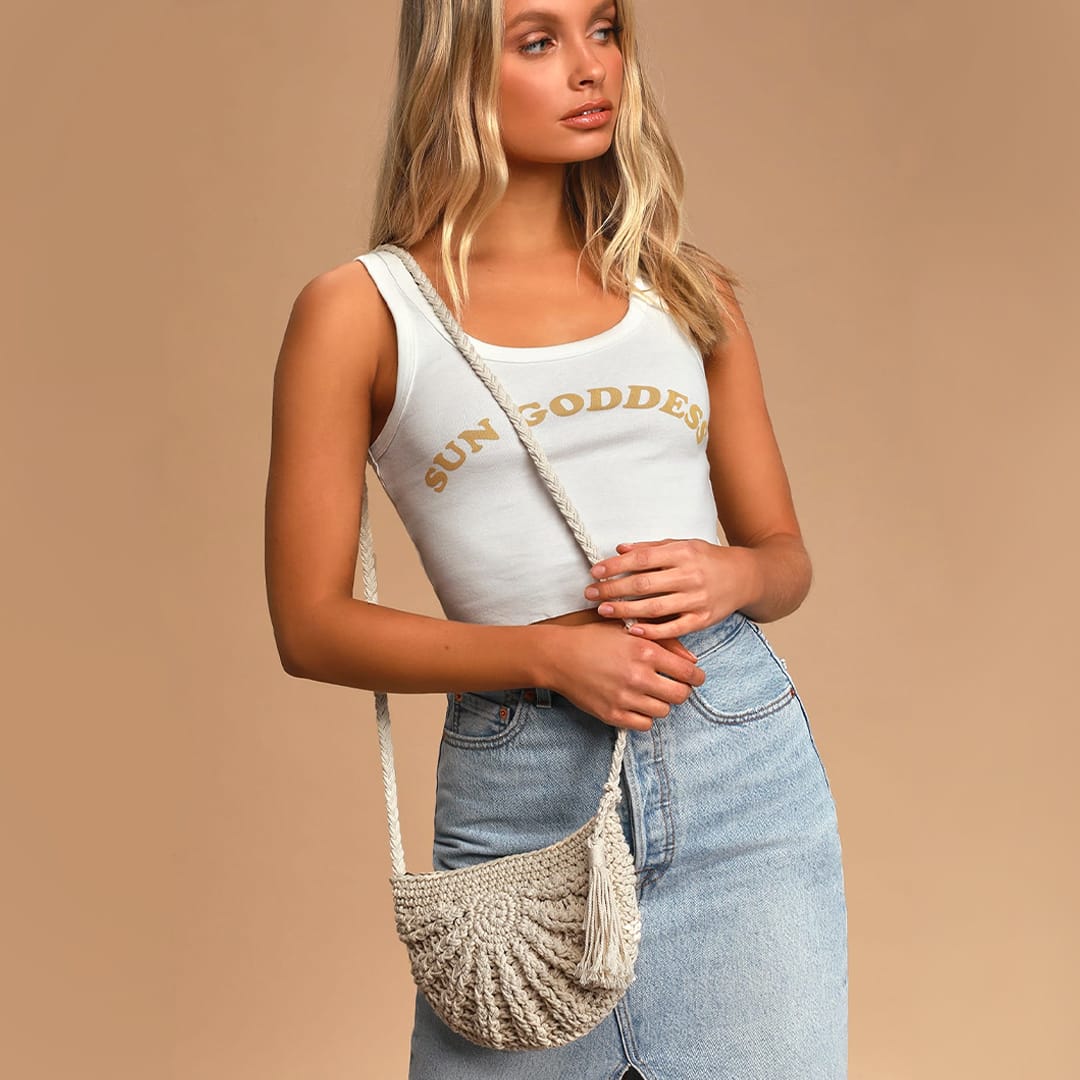 a model wearing a white tank and denim skirt with a 70s inspired woven macrame crossbody bag