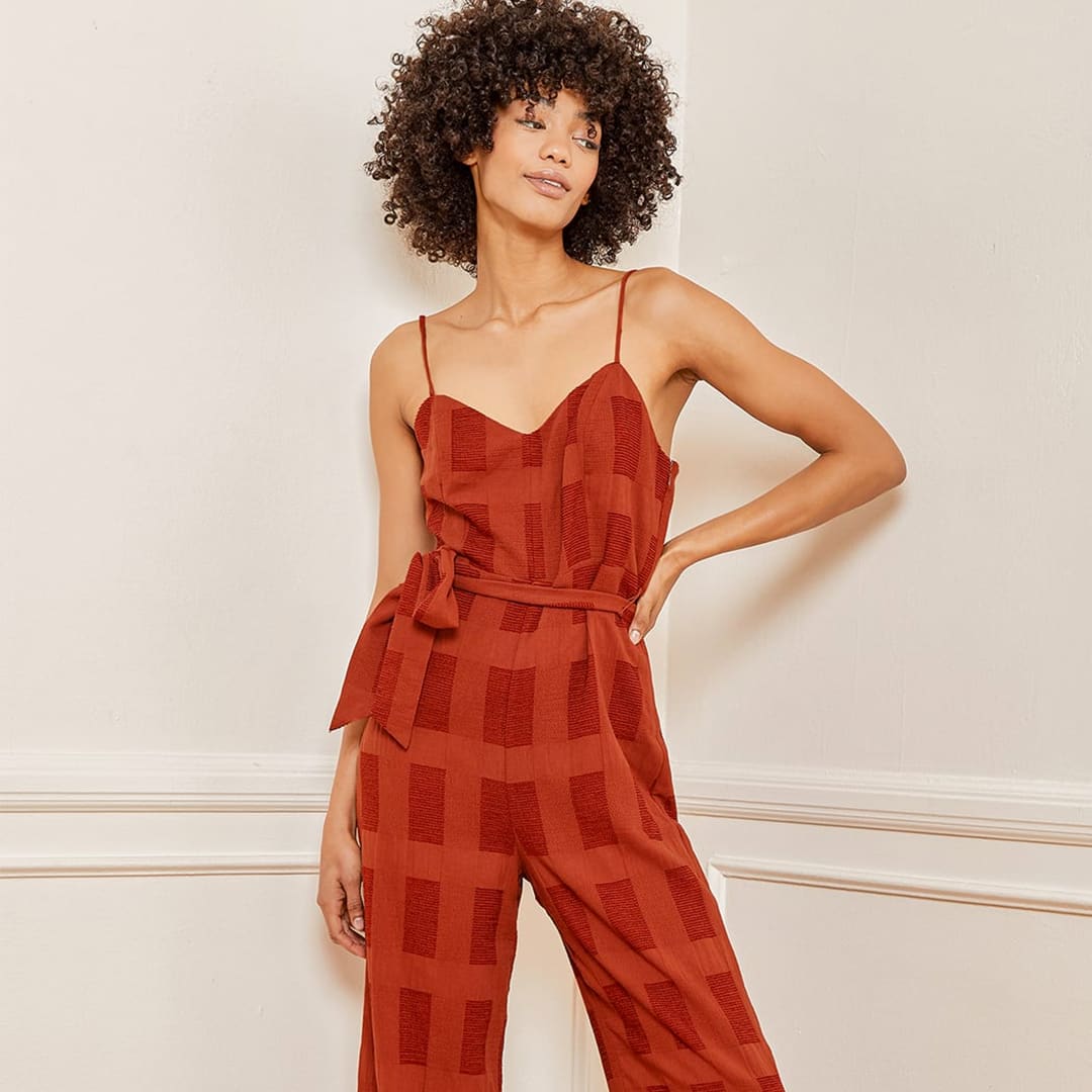 rust red culotte jumpsuit on a woman with her hand on her hip