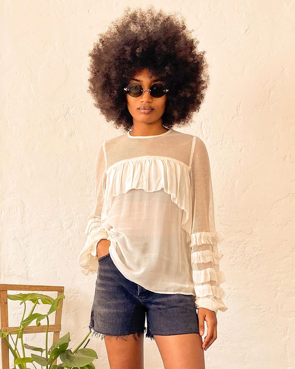 woman in ivory sheer ruffle sleeve top and shorts