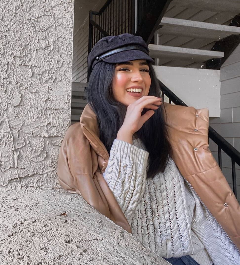 woman in baker boy cap and faux leather puffer jacket