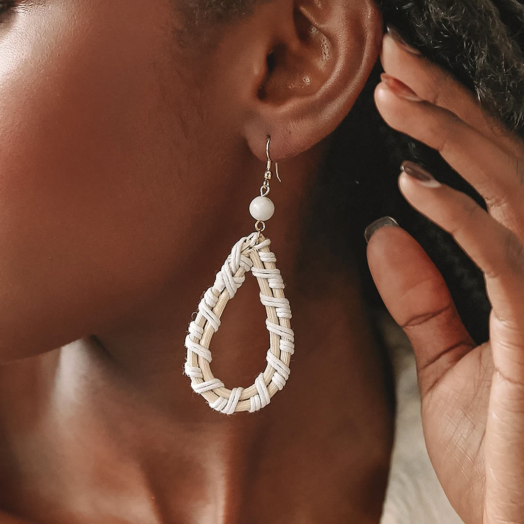 detail of a womans ear with cream wood teardrop earrings with hand touching her ear