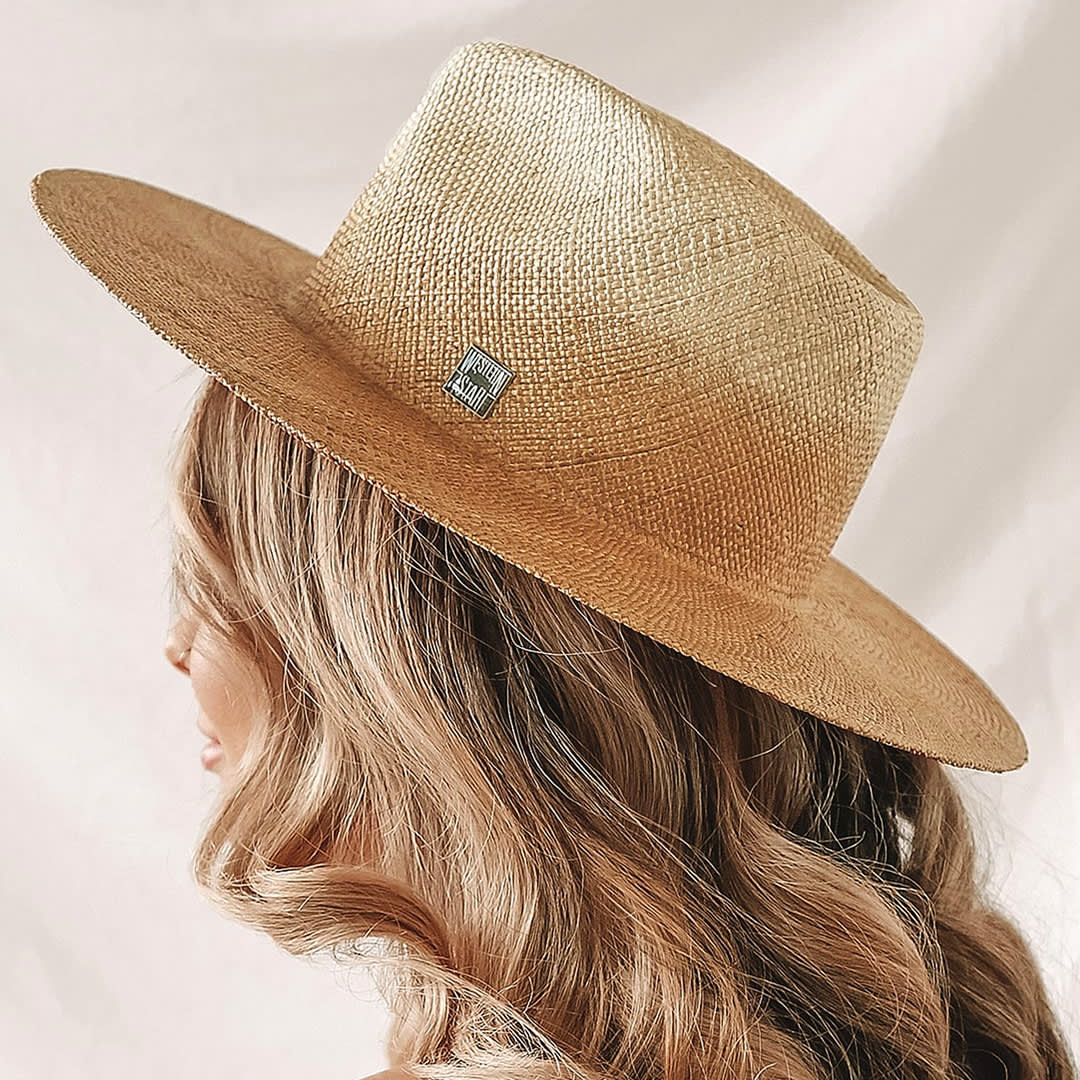 side view of a blonde woman wearing an ombre straw panama hat