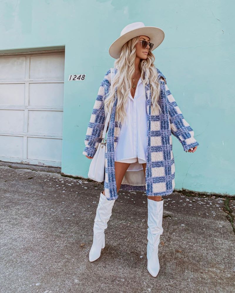 a woman in a blue and white plaid coat and over the knee white boots