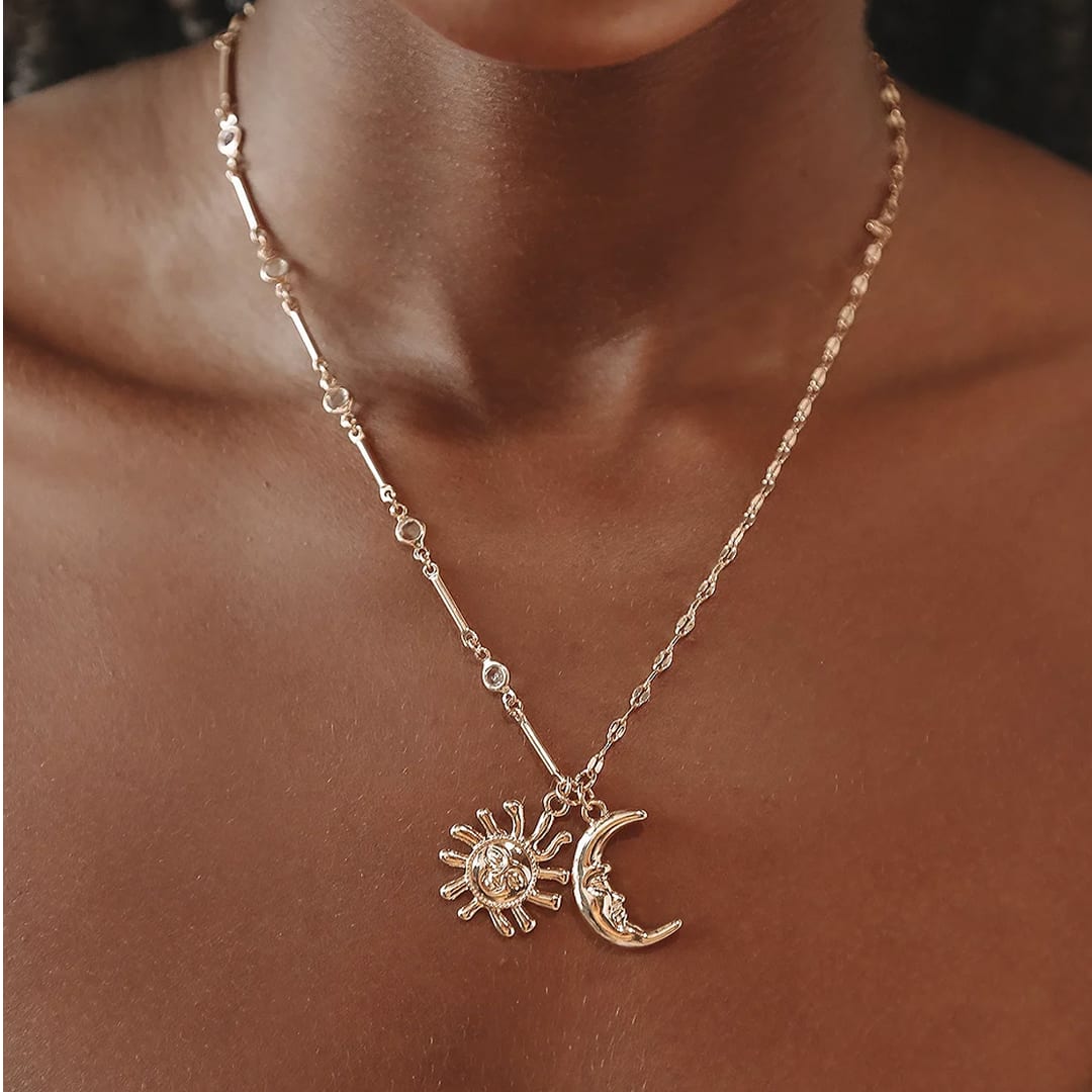a model wearing a gold sun and moon pendant necklace