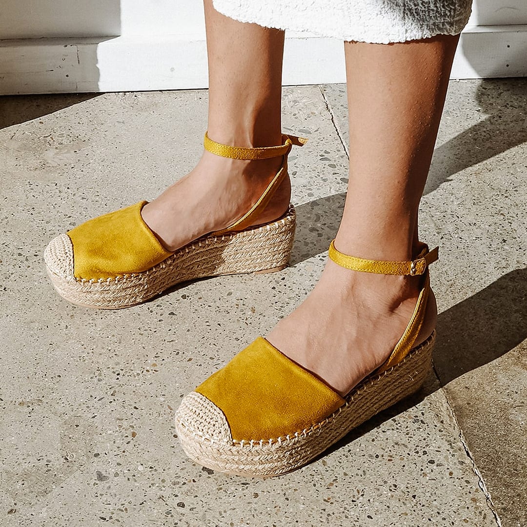 feet on a sidewalk wearing marigold suede flatform espadrilles