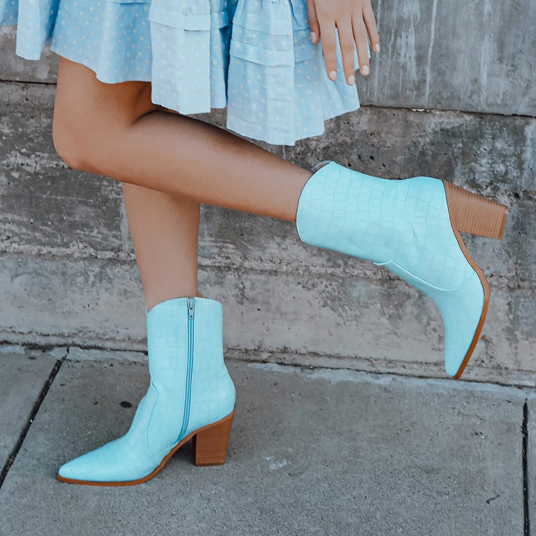 feet kicking up wearing light blue croc embossed western boots