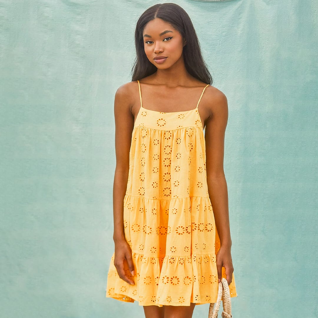 a woman in a mustard yellow eyelet lace babydoll dress