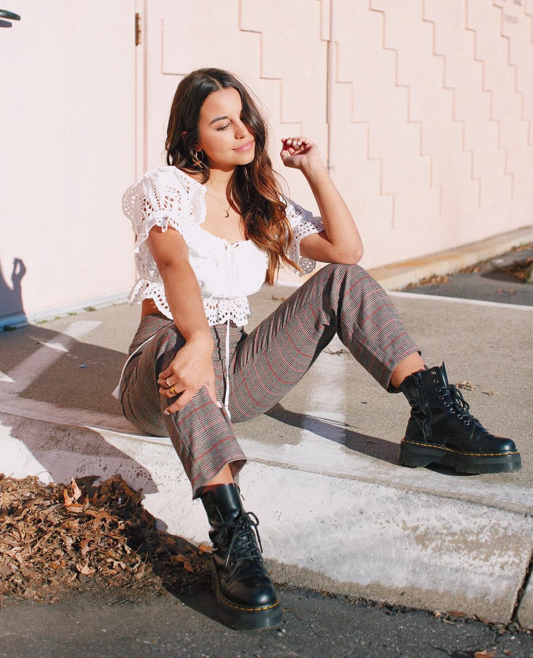 woman in white eyelet top with plaid pants and combat boots 