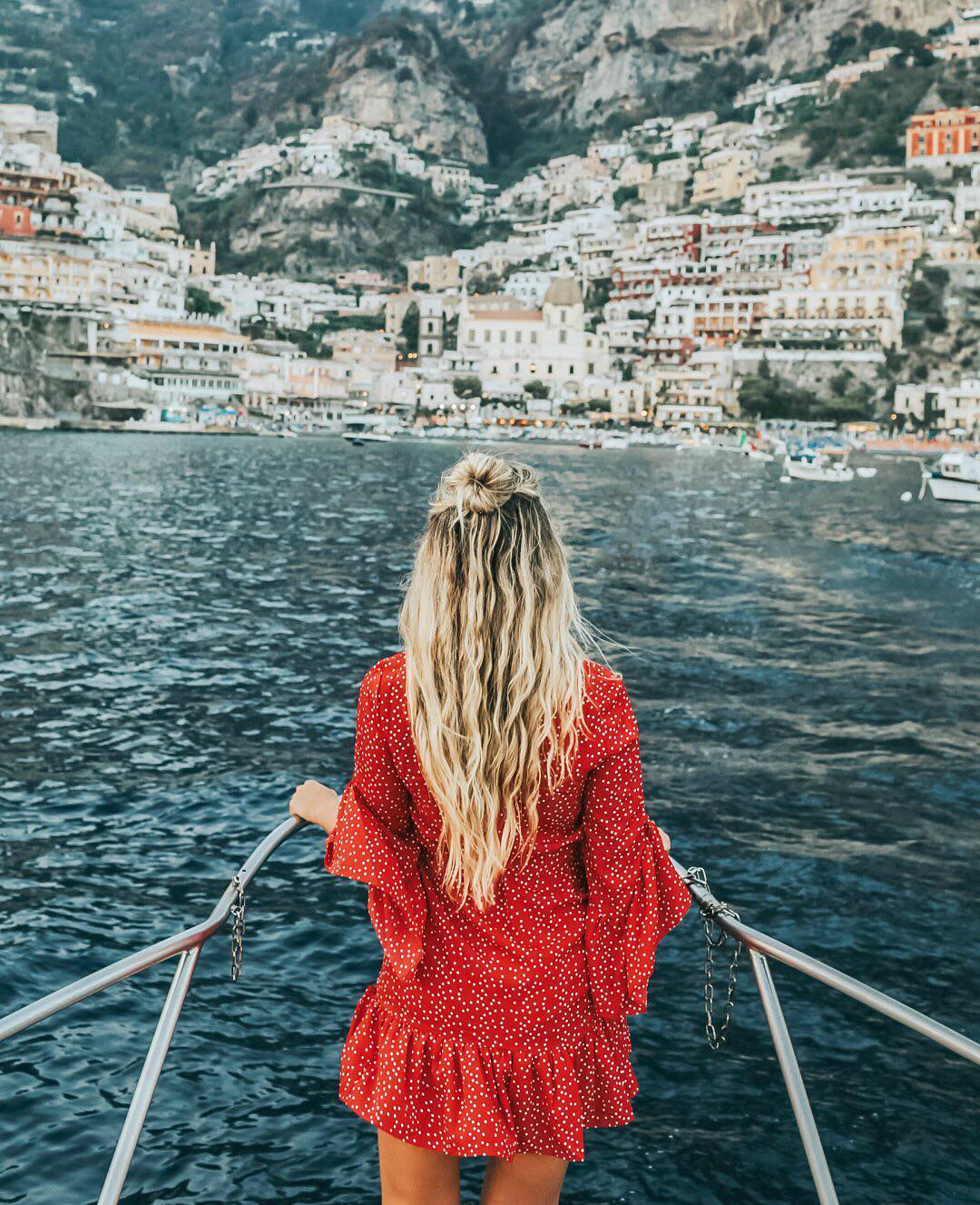 blonde woman in red dress on a boat in the amalfi coast