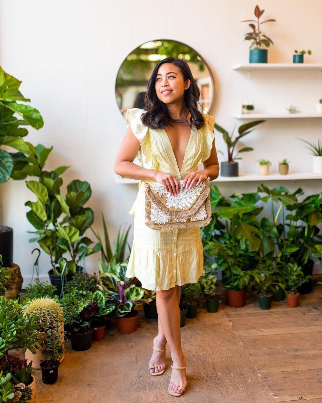 woman wearing a yellow ruffle dress and woven clutch  : yellow clothes - yellow dress outfit -yellow outfit ideas - pastel yellow dress