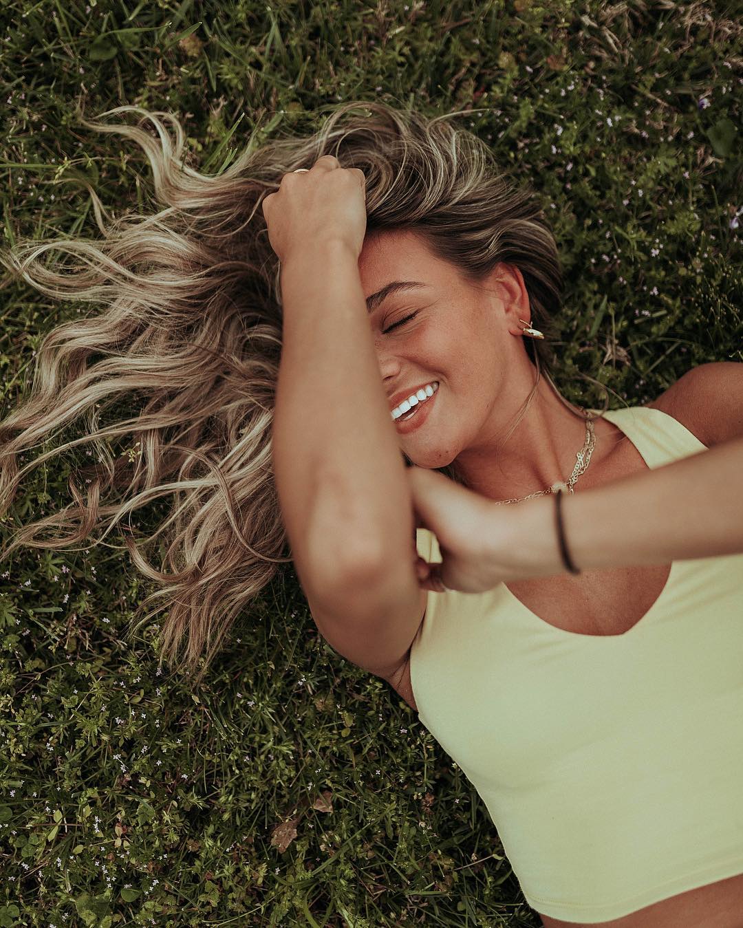 woman laying on grass in yellow crop top - natural cleaning products brands