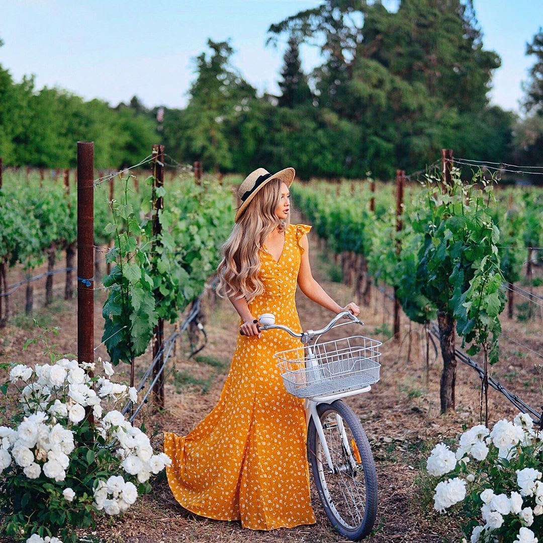 woman wearing a yellow maxi dress with a bicycle in a vineyard : natural wine : natural wine alcohol content : best natural wine