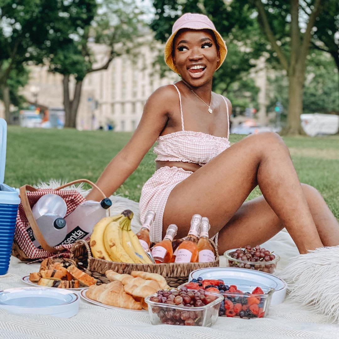 woman in gingham two piece set having a picnic and wearing a hat 