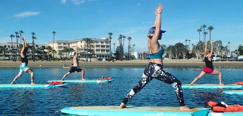 people standing on paddleboards doing sup yoga