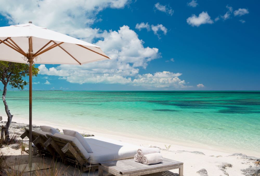 ocean and white sand beach with lounge chairs in Parrot Cay as a unique honeymoon destination