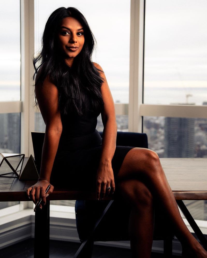 katrina xavier in a black dress sitting on a desk to show how to find your voice