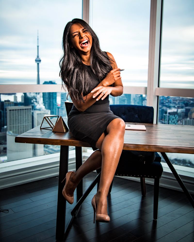katrina xavier in a black dress sitting on a desk to show how to find your voice