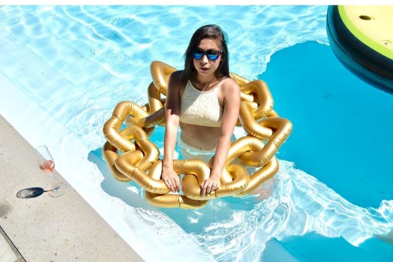 woman in a pool with an inflatablle gold chain pool float for adults