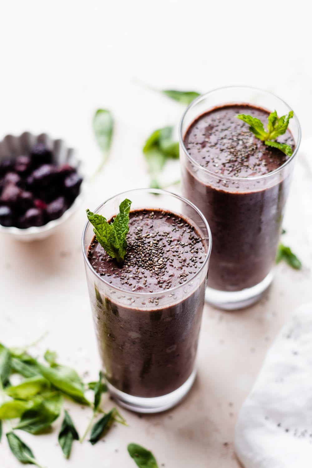 berries yogurt smoothie in two glasses with green leaves around