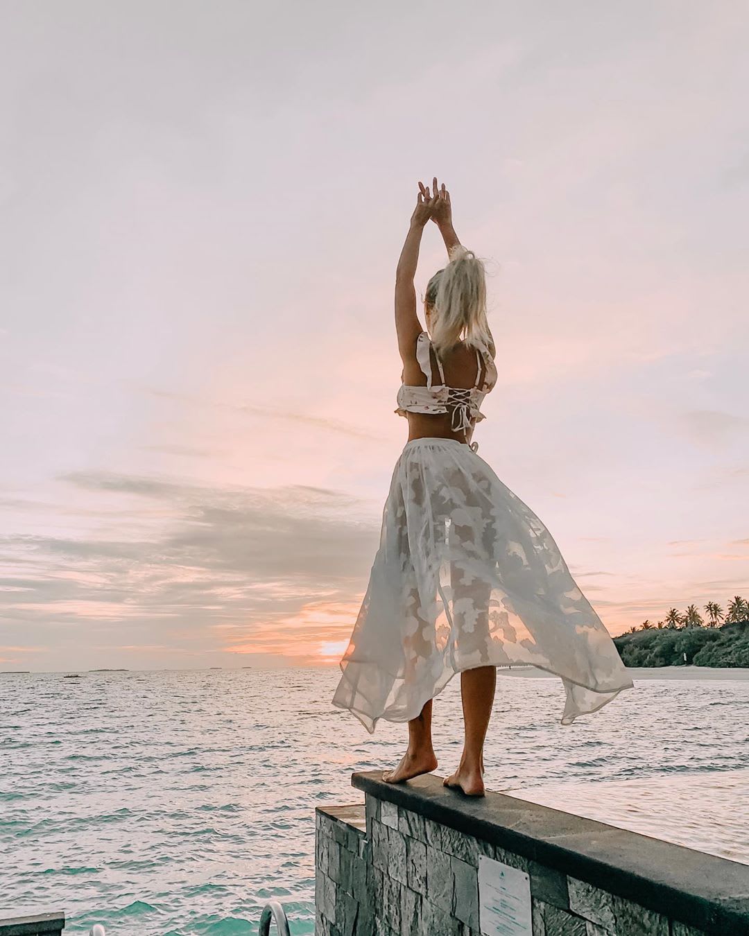 woman doing yoga on the ocean at sunrise