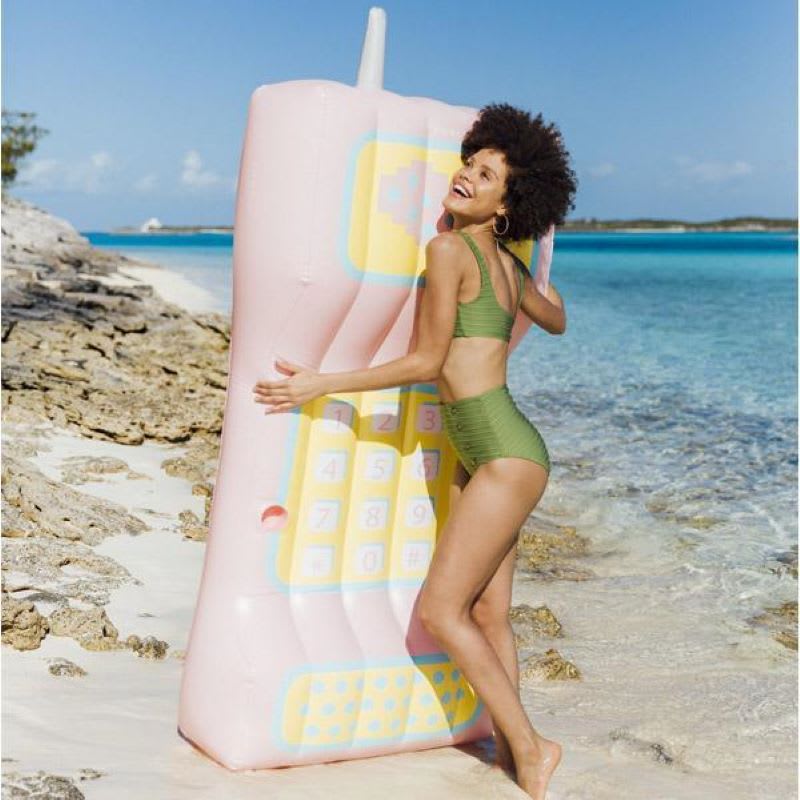 woman on the beach with retro phone inflatable pool float for adults