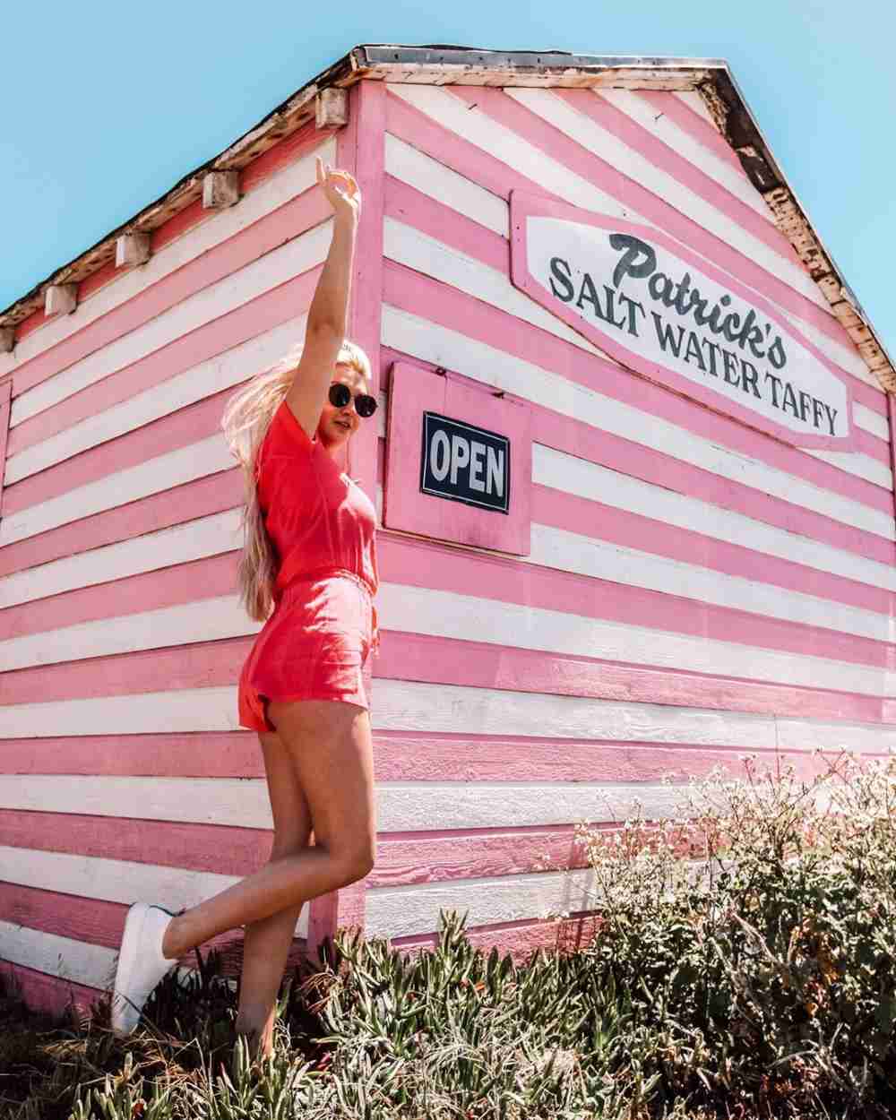 blonde woman jumping in the air wearing a coral romper
