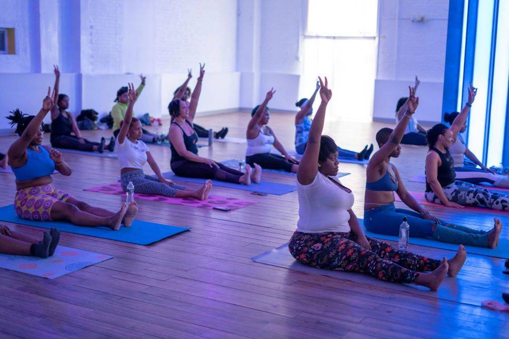 women sitting in a dark studio doing trap yoga