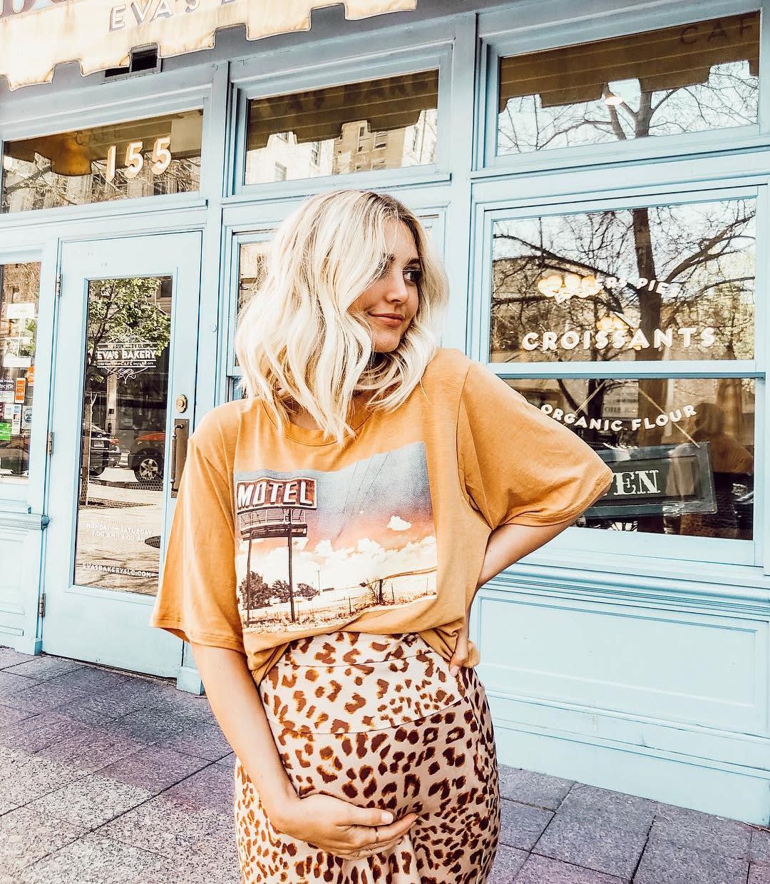 blonde pregnant woman in graphic tee and leopard skirt