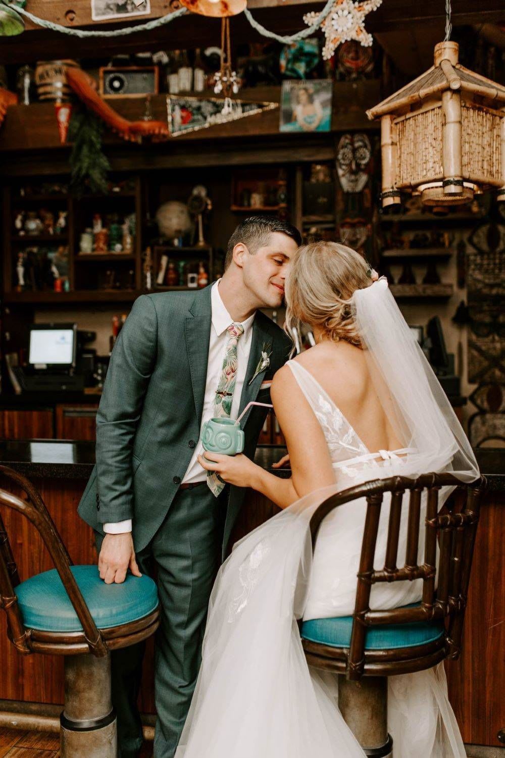 couple kissing at tiki bar during their wedding at disney