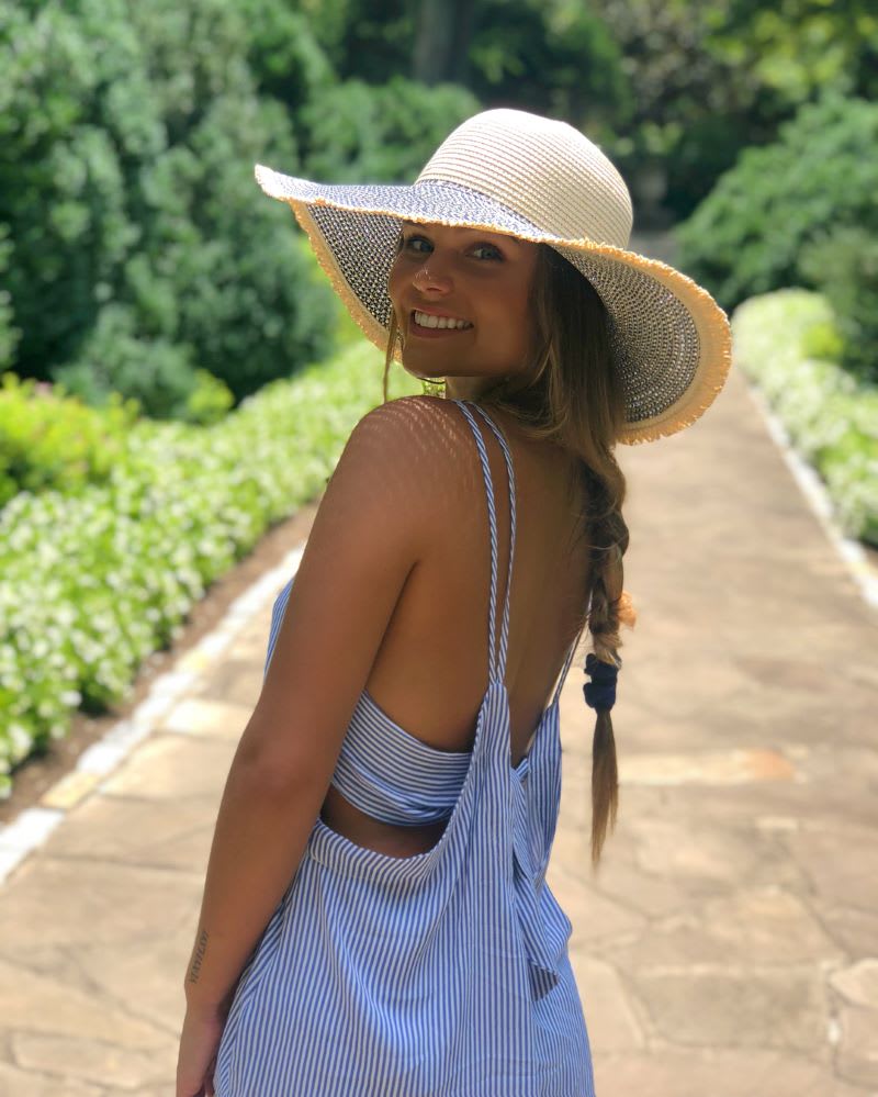 woman in a striped dress and sun hat smiling 