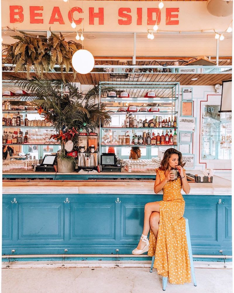 woman sitting at a beach bar sipping a drink