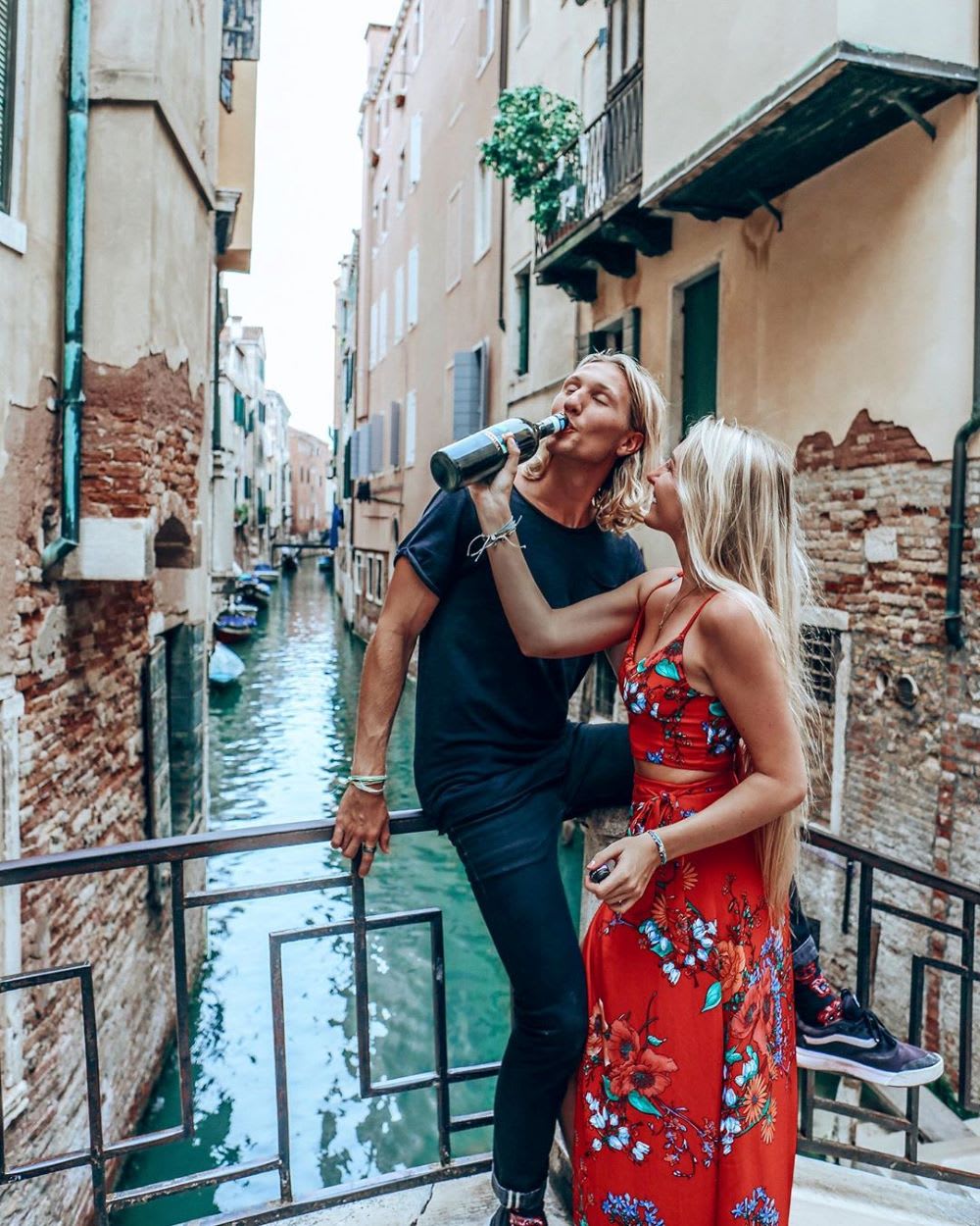 couple in venice feeding each other wine from a bottle