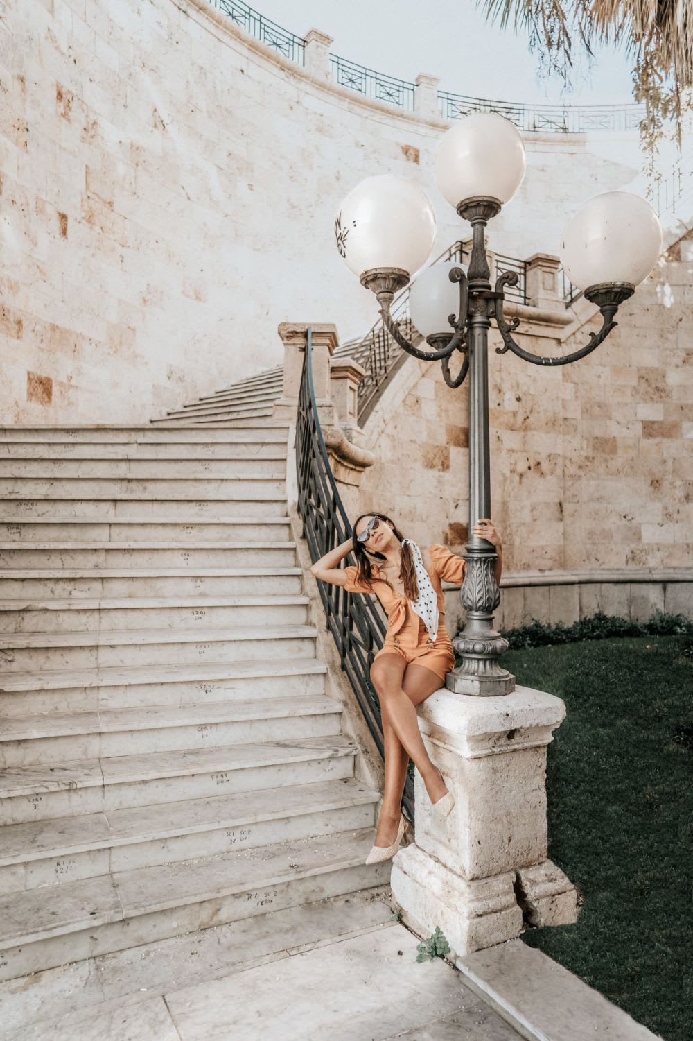 woman sitting on lamppost in Sardinia travel guide