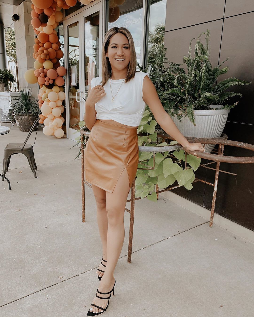 woman wearing a white muscle tank and brown vegan leather skirt