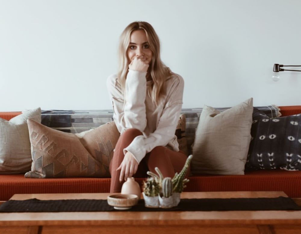 blonde woman sitting on couch with face in hands -- financial problems solutions