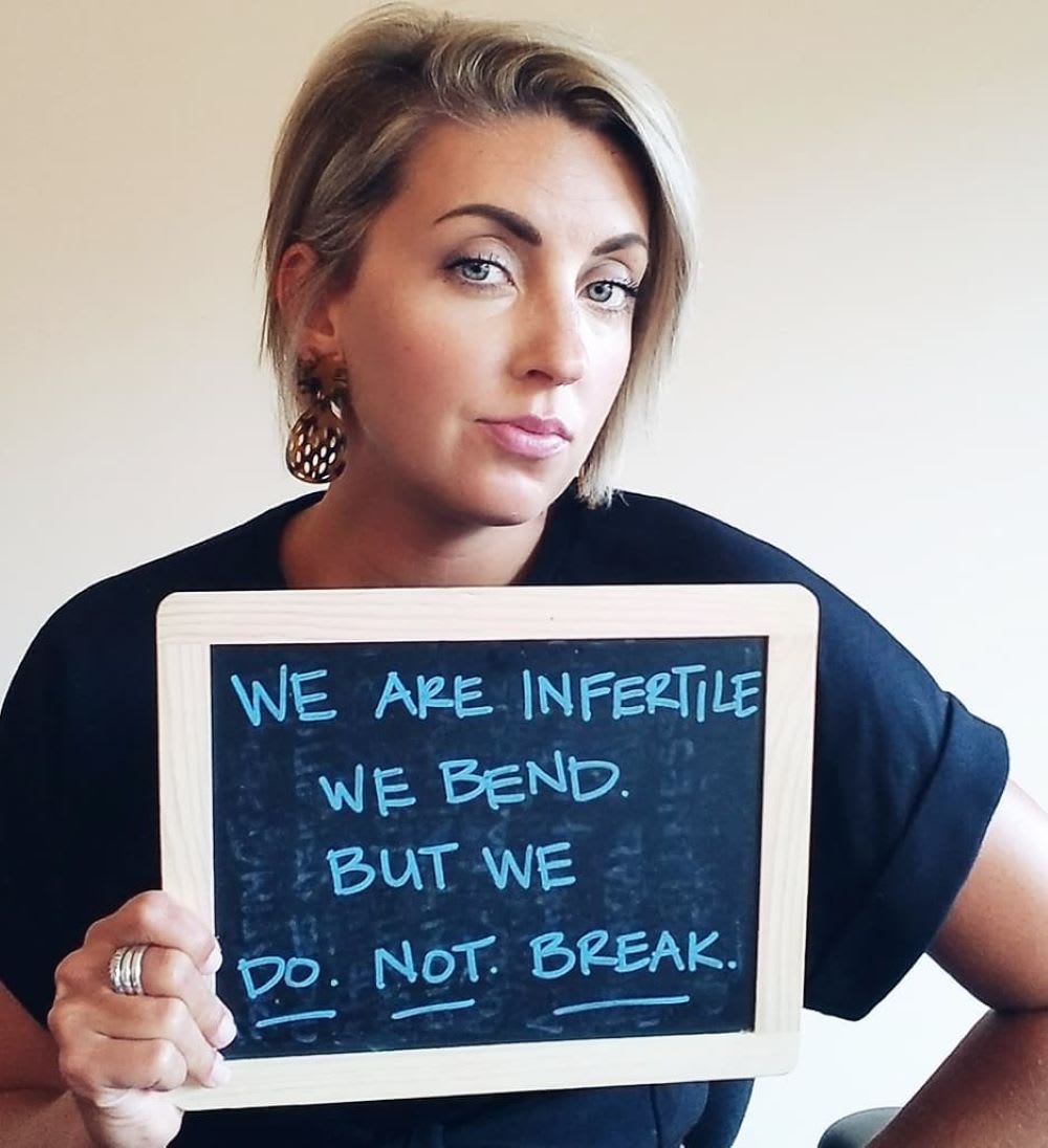 tia gendusa holds up a sign on dealing with infertility and life after ivf