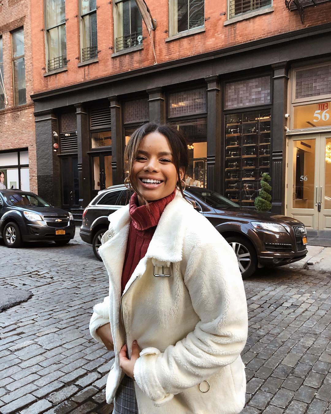 woman in cream shearling coat on street as example of holiday travel