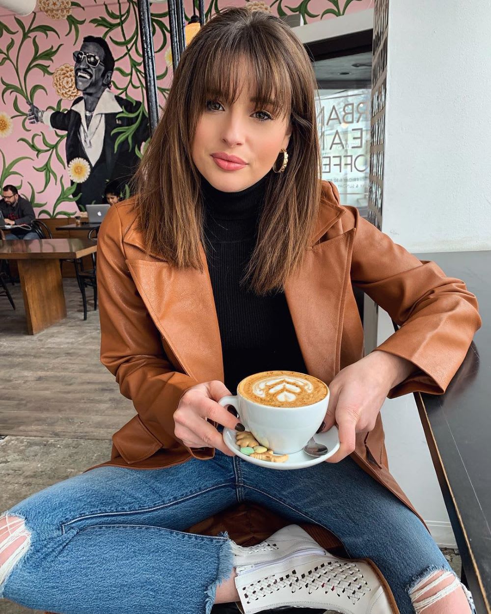 woman sipping coffee in leather jacket