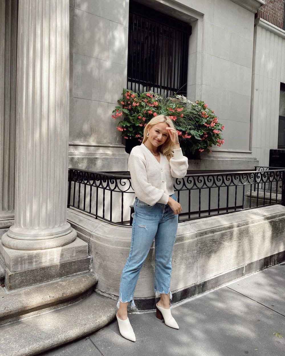 woman wearing an ivory cardigan with jeans and white mules