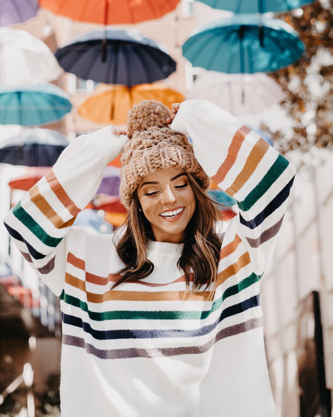 woman wearing rainbow striped sweater and beanie for giving tuesday promo