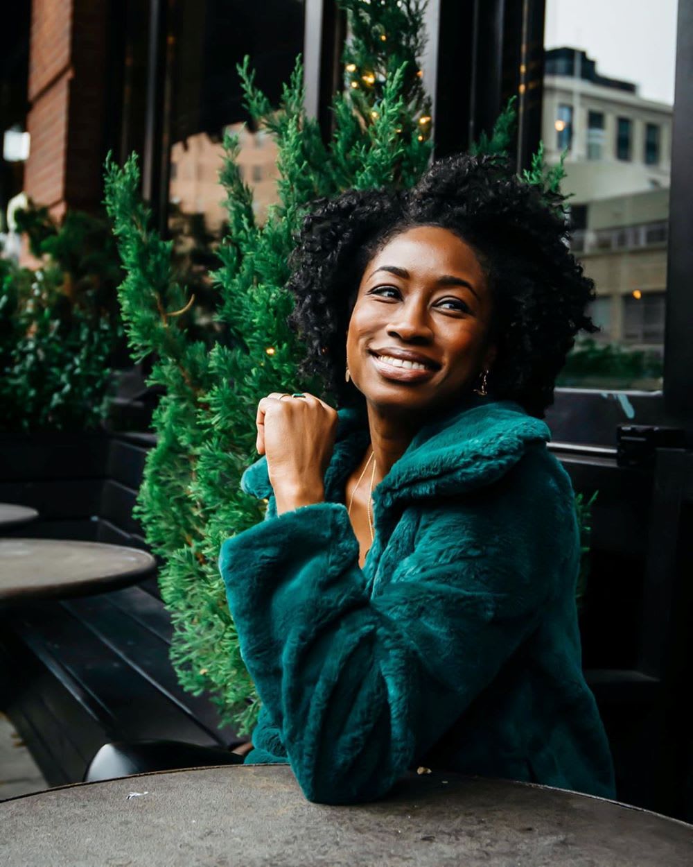 woman in faux fur green coat thinking about new year goals