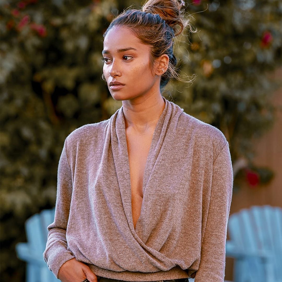 a woman with a draped plunging wrap front brown sweater with her hand on her waist