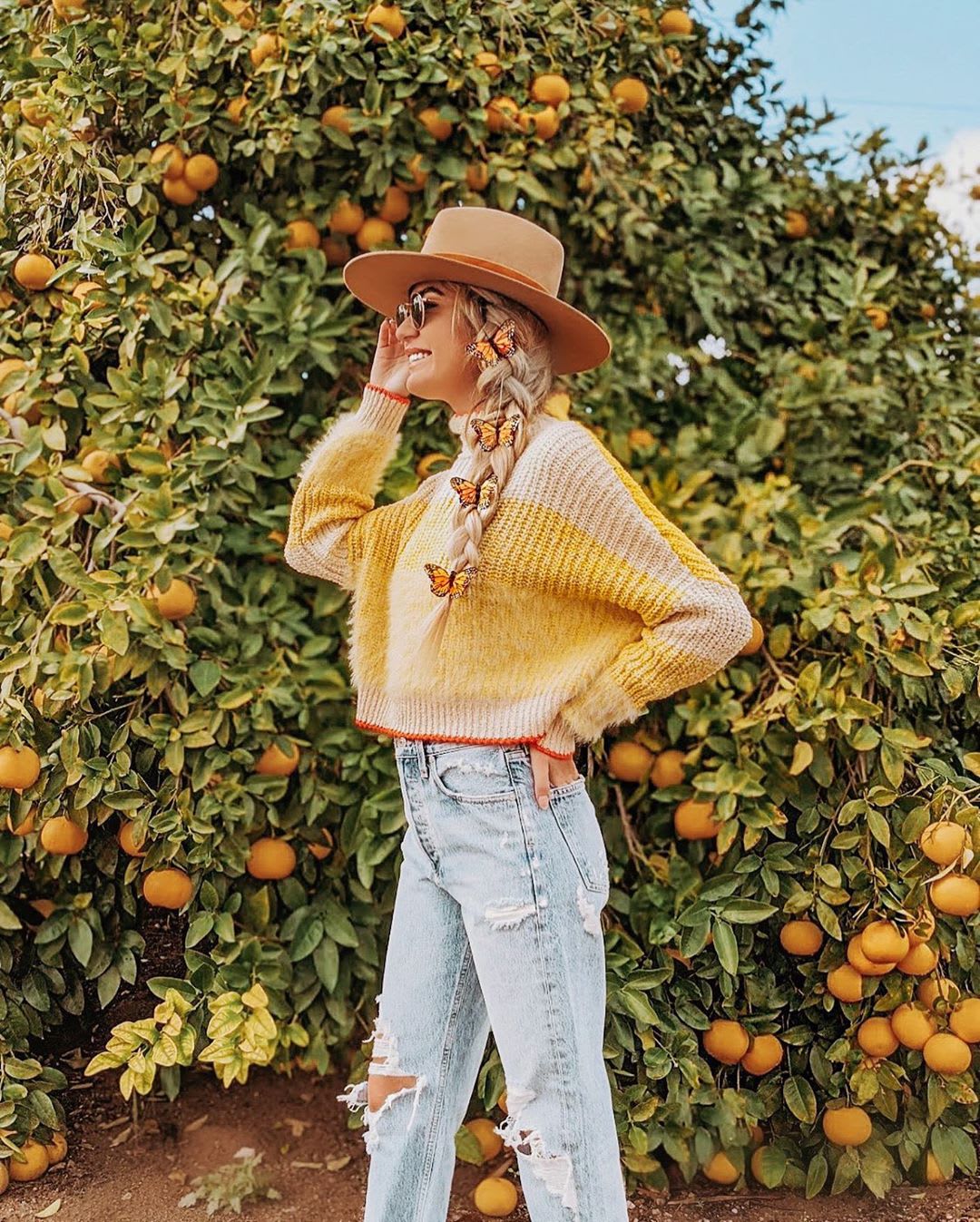 veganuary: woman in yellow sweater with butterfly braid and oranges 