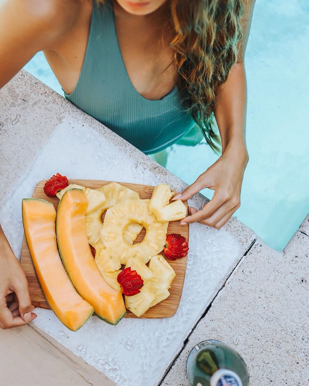 veganuary: woman eating a plate of fruit in a pool
